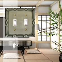 Load image into Gallery viewer, Decorative Bamboo Metal Crossed Pewter Double Toggle Wall-plate in front of a traditional Japanese living room with white rice-paper walls and minimal black coloured furnishings